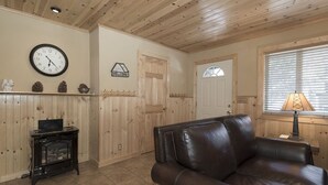 A cozy living room with a leather couch, a wooden ceiling, a clock, and a welcome sign. - Clean and fresh remodeled Lake Forest Glen End Unit (Tahoe City)