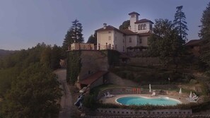 Une grande maison avec une piscine, entourée d’arbres et d ’un mur de pierre.