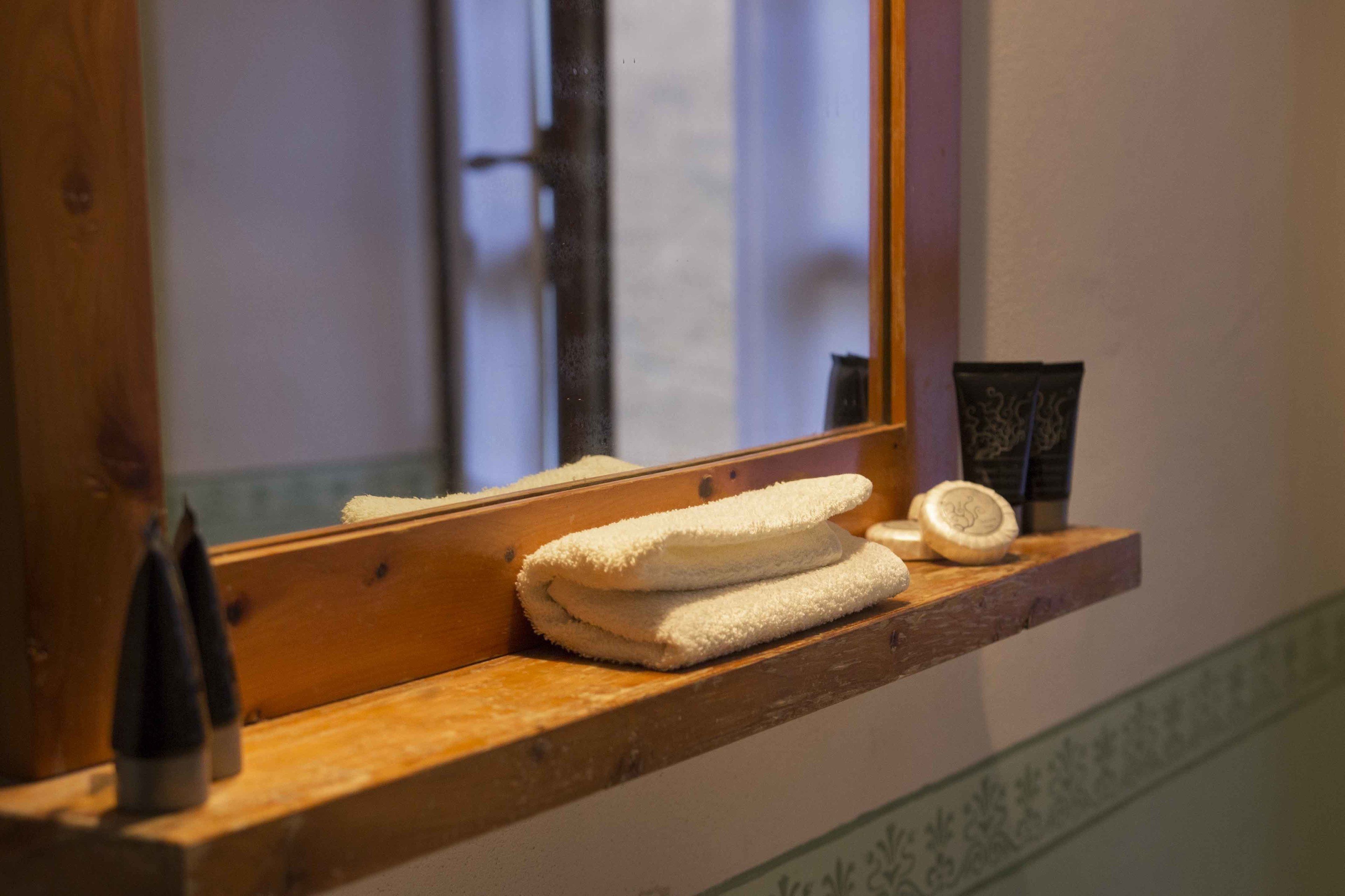 A wooden shelf with folded towels and toiletries.