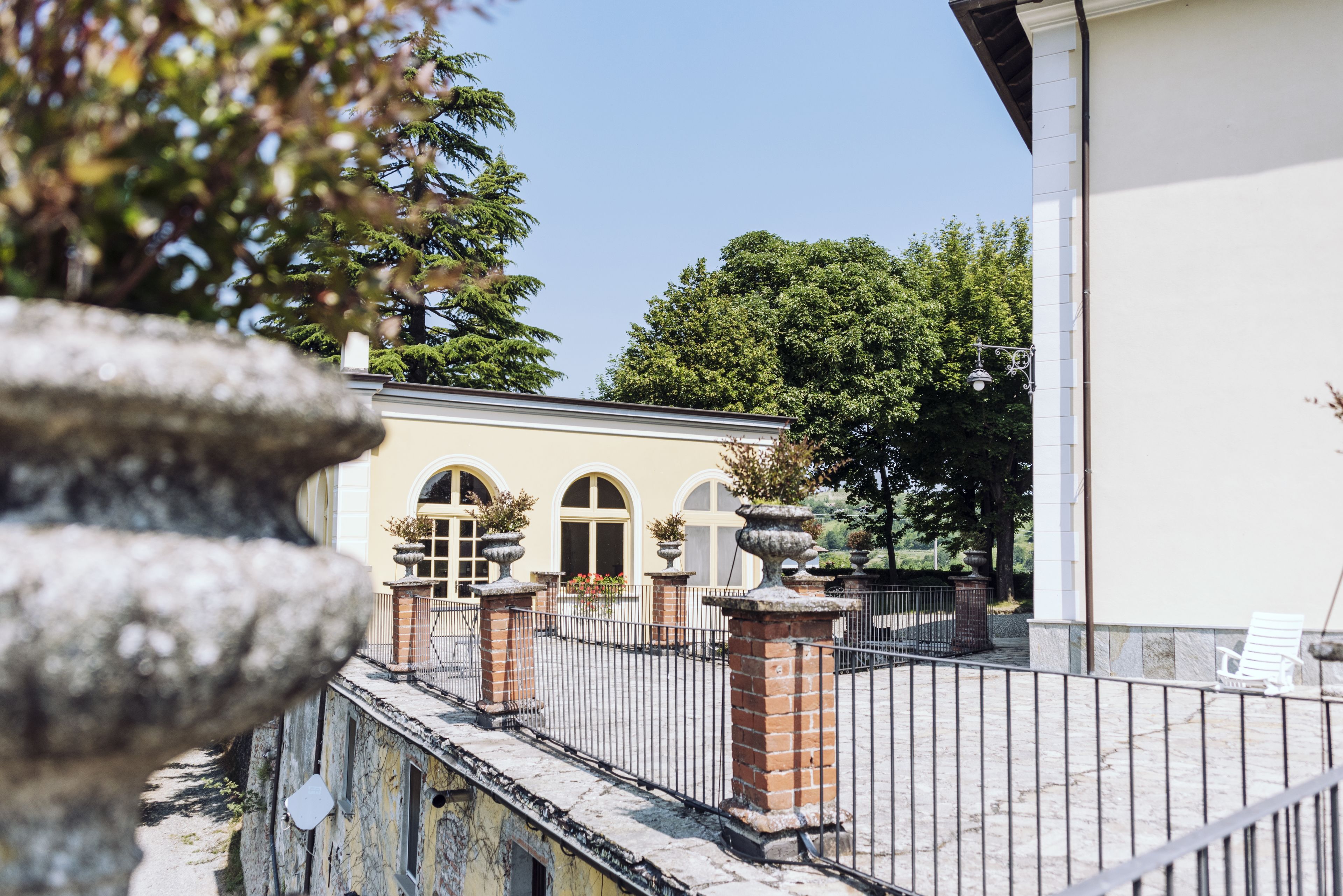 Ein Innenhof mit einer Steinmauer, einem Metallzaun und einem Gebäude mit Rundbogenfenstern.