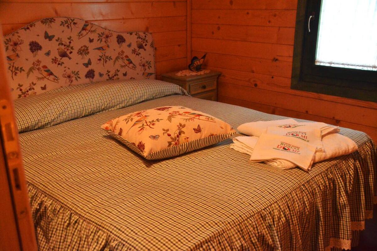 Une chambre confortable avec une tête de lit à motifs floraux, une couvre-lit à carreaux et un lit soigneusement fait, avec une serviette pliée.