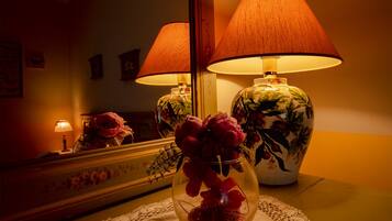 Una habitación con un espejo que refleja una lámpara y un florero con flores.