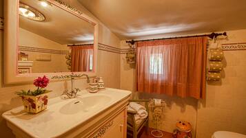 Un baño con lavamanos, espejo, tocador, inodoro y adornos.