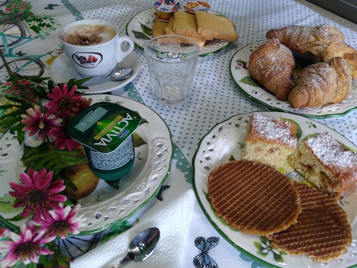 A table with plates of food, including waffles and pastries, a cup of coffee, and a container of tea.
