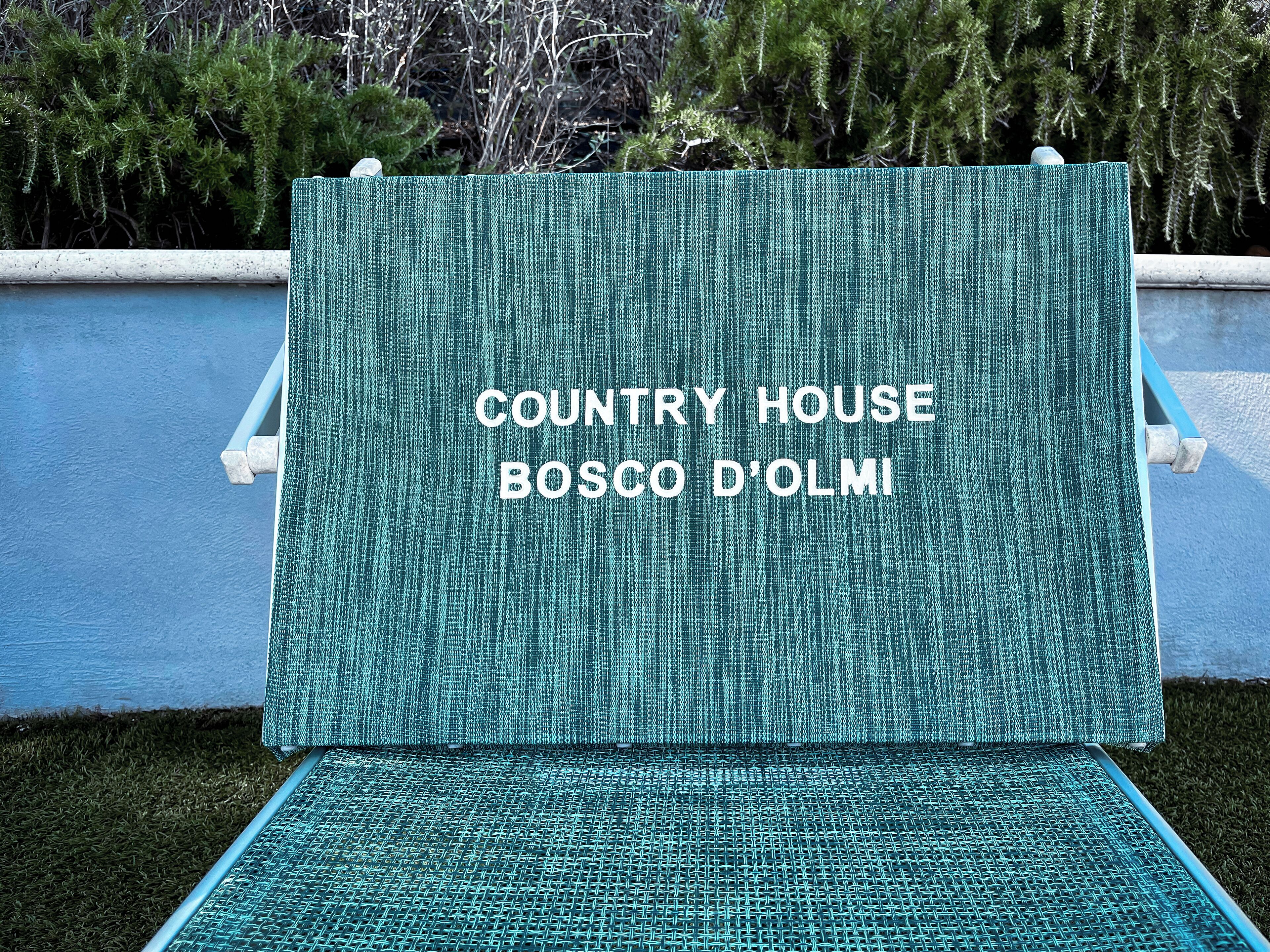 Un espacio de estar verde al aire libre con el texto "COUNTRY HOUSE BOSCO D'OLM".