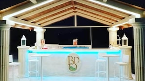 A bar area with a pool, white columns, and a logo on the counter.