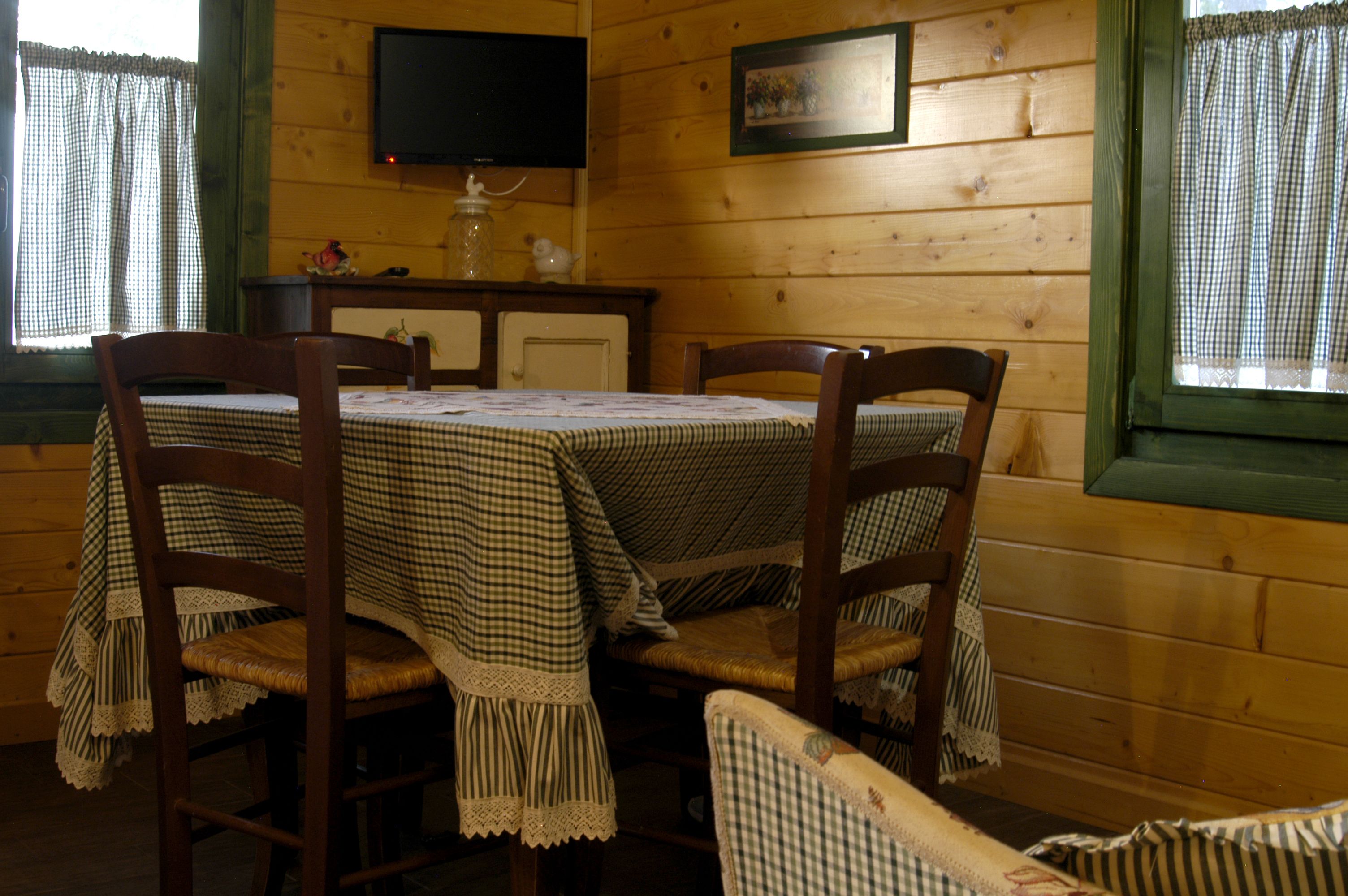 A wooden cabin with a dining table set for four, surrounded by wooden chairs.