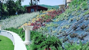 A landscaped garden with a curved pathway, a white column, and a variety of plants and shrubs.