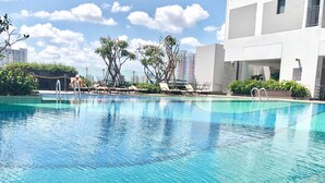 A swimming pool with lounge chairs and a building in the background. - Trip Apartment Saigon (Ho Chi Minh City)