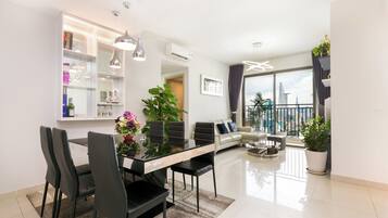 Un salon moderne comprenant un coin repas, un canapé et un balcon offrant une vue sur la ville.