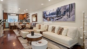 A modern living room with a white sofa, round coffee table, and a large winter-themed painting on the wall. -  Aspen Core Designer 4 Bdrm, Walk to Everything , A/C, Parking (Aspen)