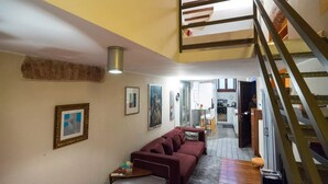 Una sala de estar con un sofá, una mesa de centro y una escalera que sube a un nivel superior.