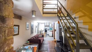 Una sala de estar moderna con una mesa de centro de vidrio, un sofá y una escalera con barandilla de metal.