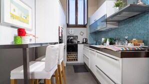 Una cocina moderna con armarios blancos, encimera de acero inoxidable y ventana sobre el lavamanos.