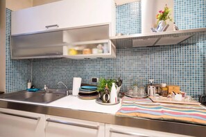 Een keuken met een roestvrijstalen spoelbak, witte kastjes en een backsplash van blauwe tegels.