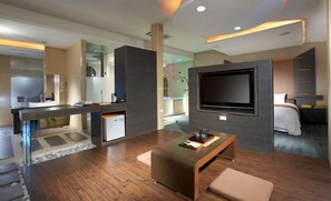 A modern hotel room with a large flat-screen TV, a wooden coffee table, a comfortable sofa, and a separate sleeping area with a bed. - Hofi Villa (Toucheng)