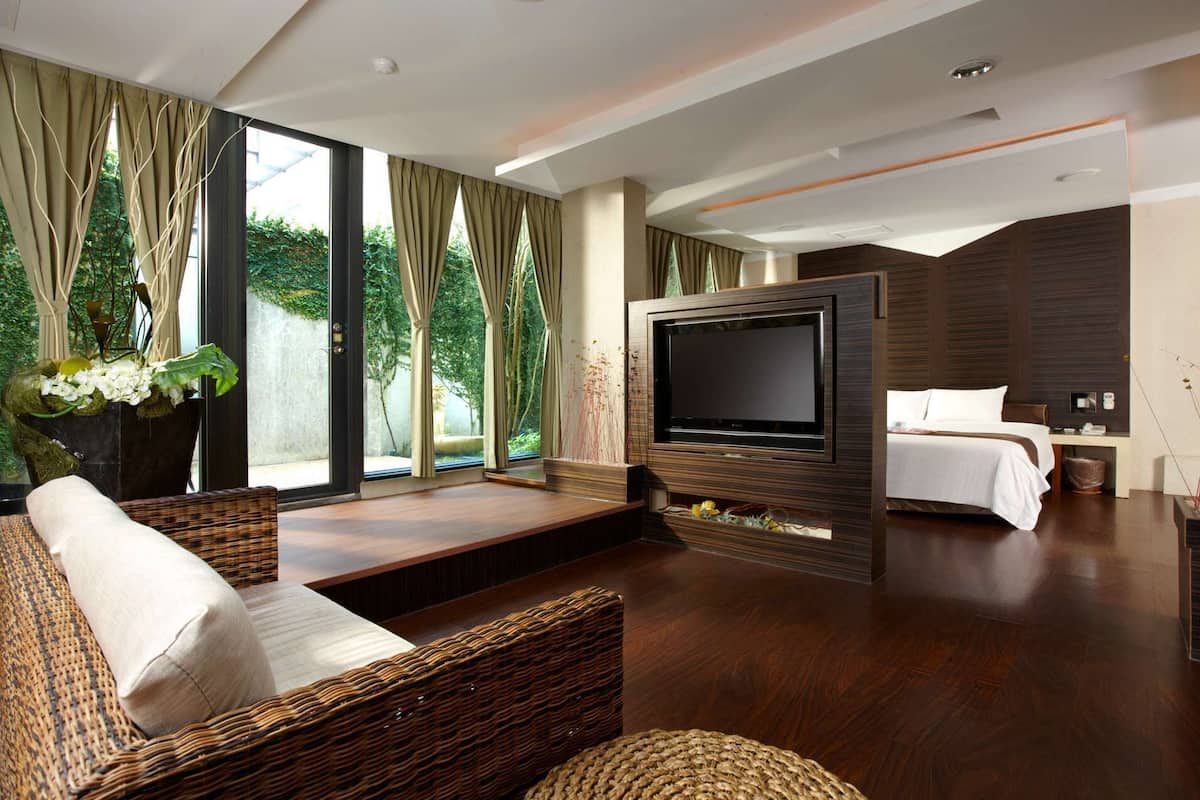 Una habitación de hotel moderna con una tele grande, asientos cómodos, una cama y vistas a zonas verdes.