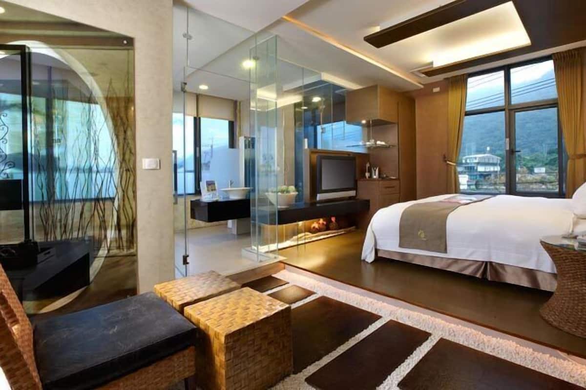 Una habitación de hotel moderna con una cama grande, televisión, chimenea y vistas a la ciudad.