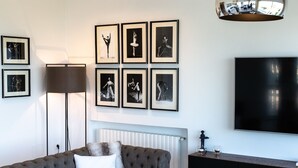 Ein modernes Wohnzimmer mit einer Eckcouch, einem Couchtisch, einer Stehlampe und einem an der Wand befestigten Flachbildfernseher.