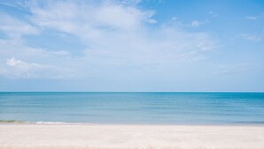 Een strand met heldere lucht en een kalme zee.