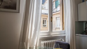 A room with a window, a radiator, a glass table, and a framed picture on the wall. - Disciplini (Milan)