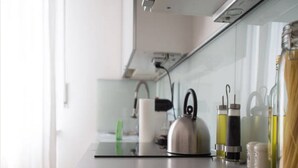 A kitchen counter with a kettle, a roll of paper towels, and various bottles. - Disciplini (Milan)