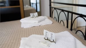 A neatly made bed with folded white towels and a small card on each. - Disciplini (Milan)