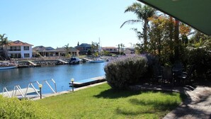A marina with boats docked, a grassy area, and a pathway leading to a building with a view of the water. - Marina's Holiday Retreat (Port Lincoln)