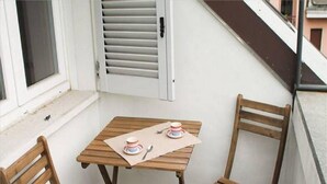 Une petite table en bois avec deux chaises sur un balcon.