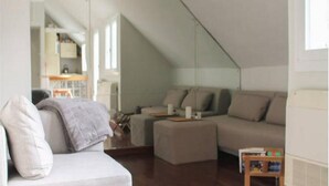 Un salon de style industriel, avec un plafond haut, un canapé, une table basse et une petite table d’appoint en bois.