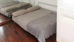 Une petite chambre avec un lit simple, un plafond en pente et un plancher en bois.
