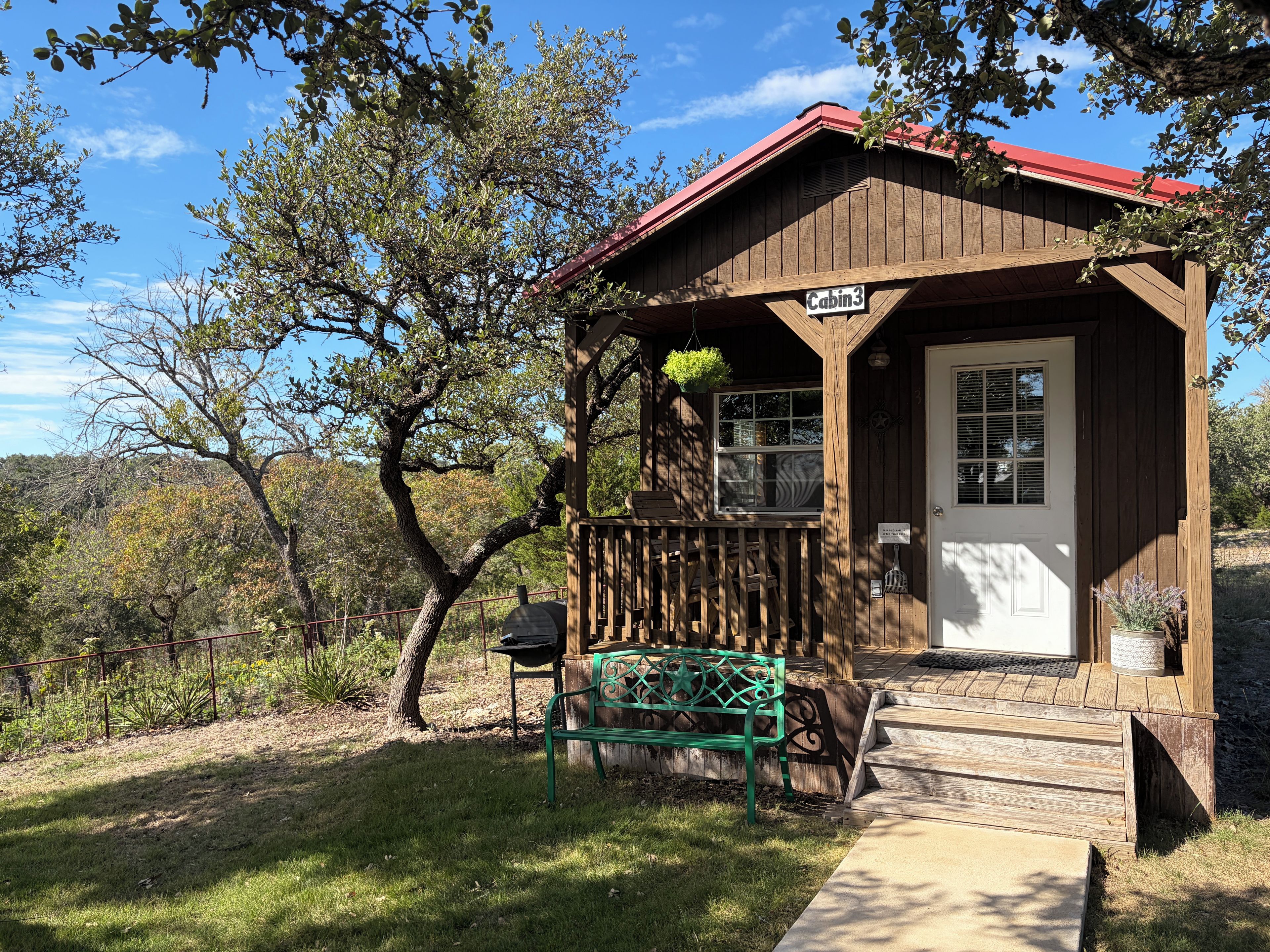 A cabin with a porch, a bench, and a sign indicating 'Cabin 3'.