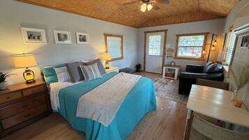 A bedroom with a bed, bedside tables, a desk, and a ceiling fan.