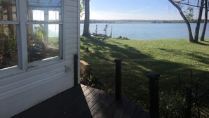 Uitzicht op een meer vanaf een huis met een terras, een schommel en een gazon.