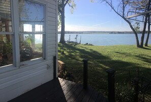 Blick auf einen See von einem Haus mit Terrasse, Schaukel und Rasenfläche.