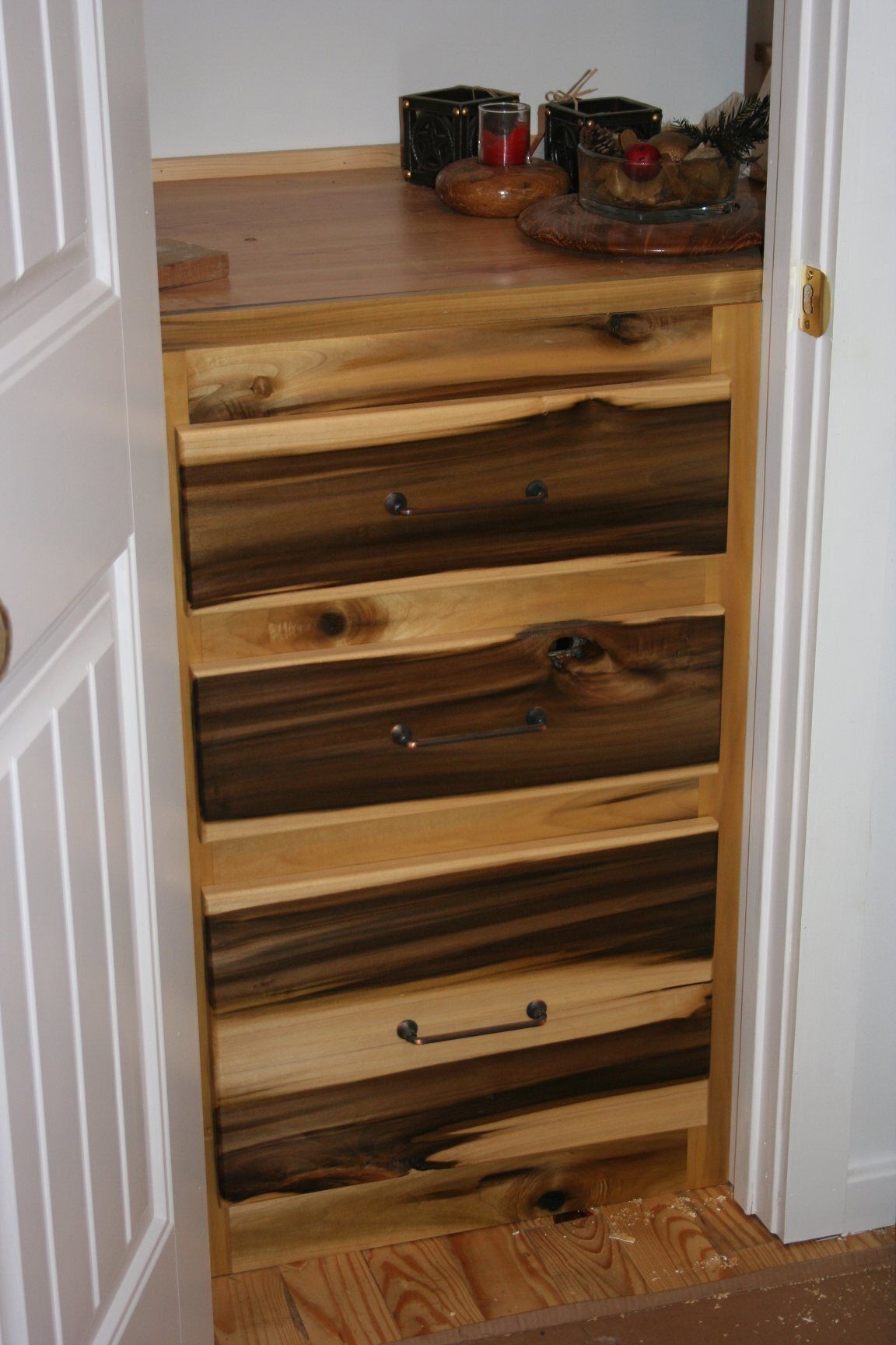A wooden chest of drawers with five drawers, each with a metal handle.