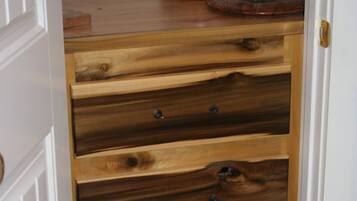 A wooden chest of drawers with five drawers, each with a metal handle.