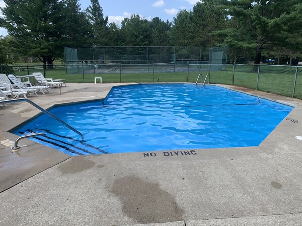 Una piscina con un cartel que dice 'NO DIVING', rodeada por una cerca y árboles.