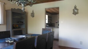 Zona pranzo con un lampadario, soffitto in legno e vista sulla cucina.