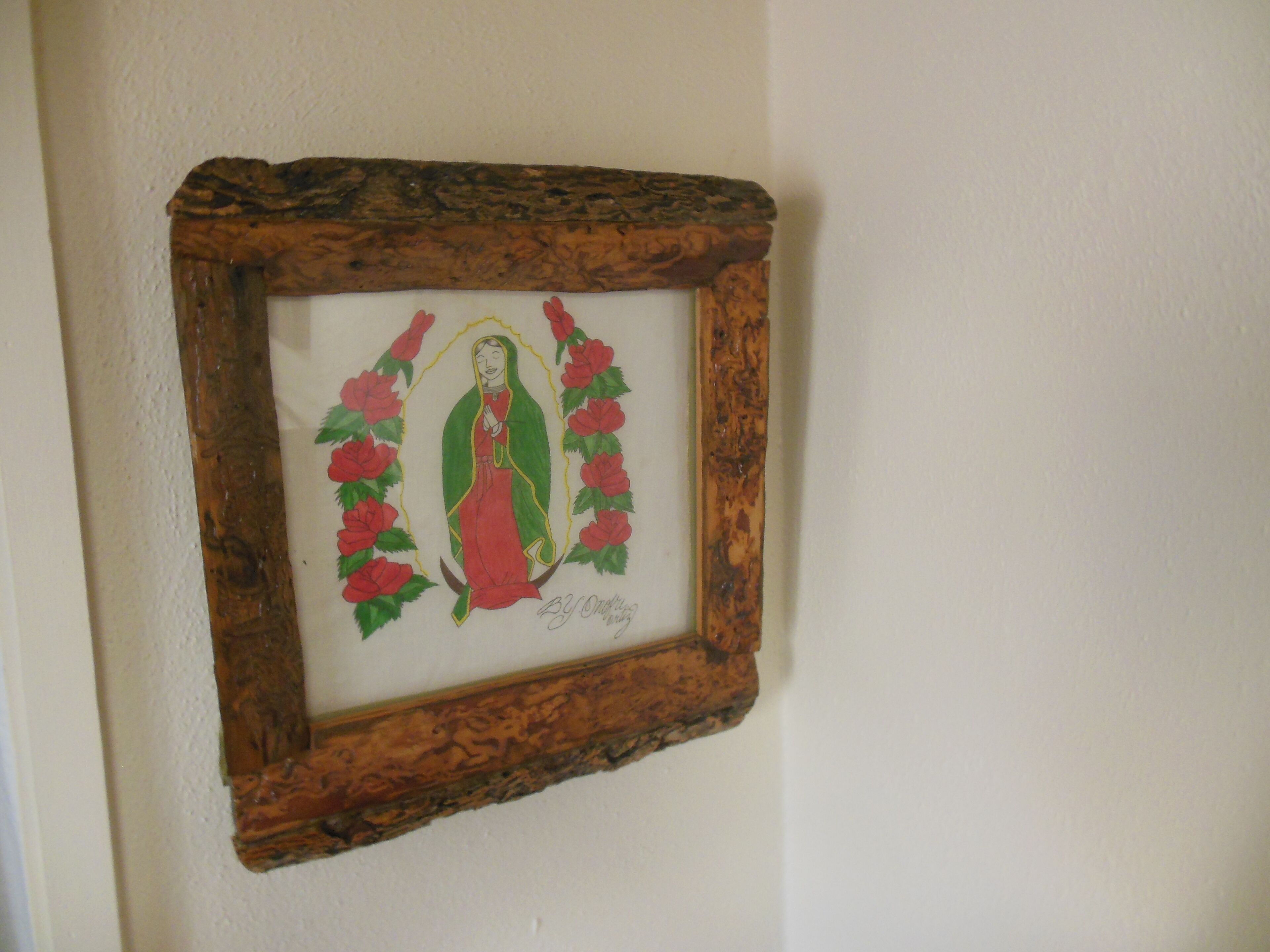 A framed artwork of a religious figure surrounded by flowers, mounted on a wall.