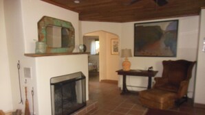 Un soggiorno con camino, una poltrona, un tavolo e un quadro appeso al muro.