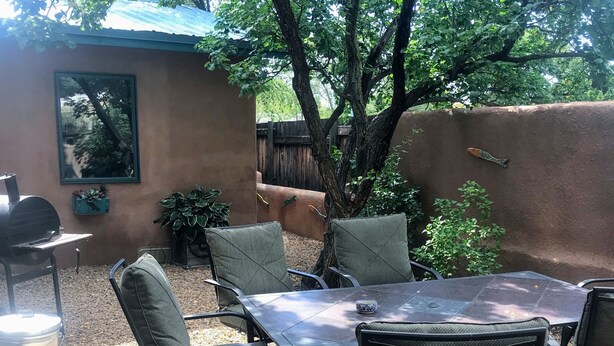 Un patio con tavolo e sedie, un barbecue e un quadro appeso al muro.