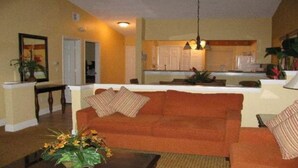 A living room with a sofa, a coffee table with flowers, and a kitchen in the background. - Orange Lake Resort: Next to Disneyworld, Near Universal, Sea World & Legoland  (Kissimmee)