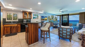 A modern kitchen with a bar area, wooden cabinets, and a view of the ocean.