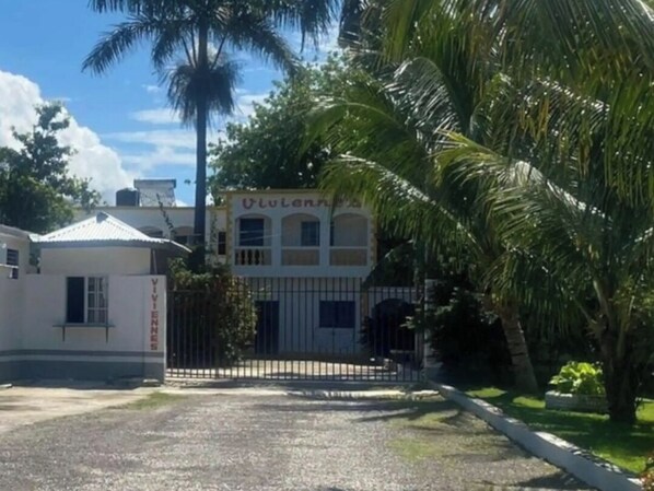 Un edificio con una entrada porticada, un letrero que dice 'VIVIENNES' y una palmera en primer plano.
