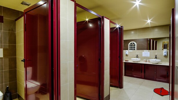 Un baño de hotel con diseño moderno, que incluye un inodoro, lavamanos y un espejo.