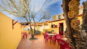 An outdoor patio area with yellow walls, red chairs, and a table with a Coca-Cola logo. - Albergue Vía Láctea - Hostel (Arzua)