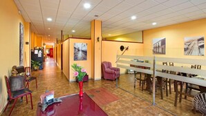 A hotel lobby with a reception desk, seating area, and artwork on the walls. - Albergue Vía Láctea - Hostel (Arzua)