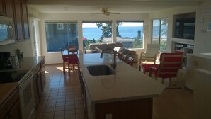 A spacious kitchen with a large island, a dining area, and a view of the ocean.