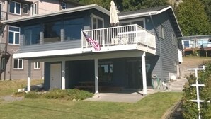 A two-story house with a covered porch and a flag.